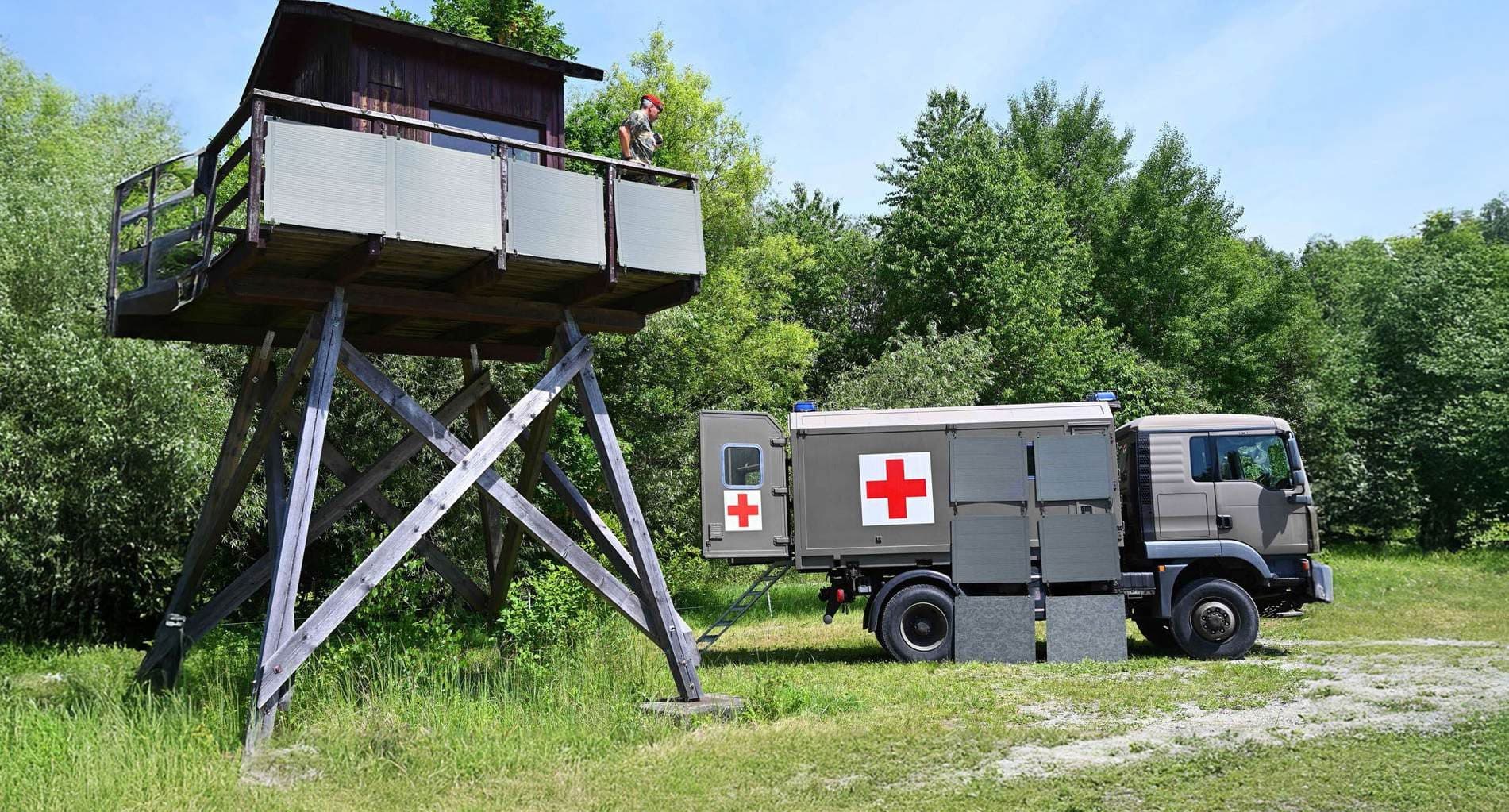 Einsatzfahrzeug mit Rotkreuz-Kennung neben einem Wachturm