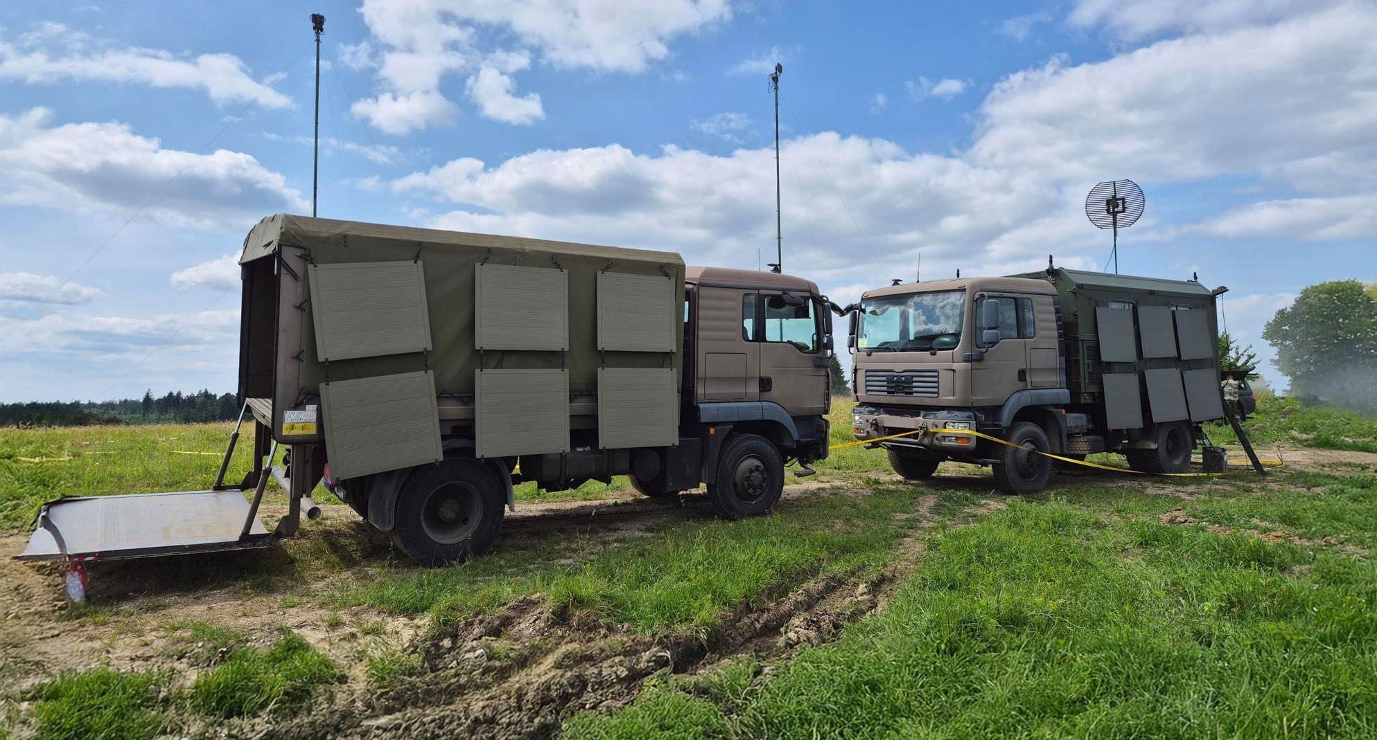 Zwei Militär-LKW mit Antennenmast und Satellitenschüssel